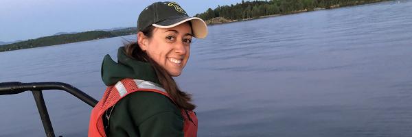 Hannah Lachance holds fish on boat on lake